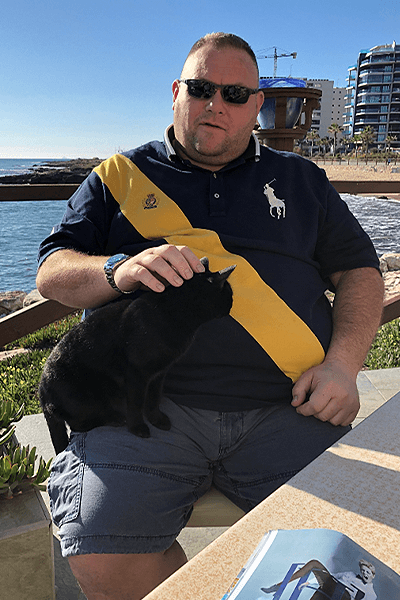 man sat by the water with cat