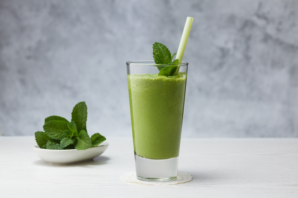 green smoothie with straw and mint leaves