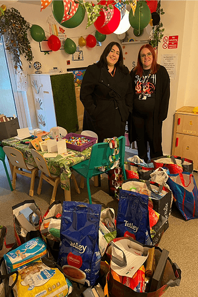 two women smiling with bags of gifts