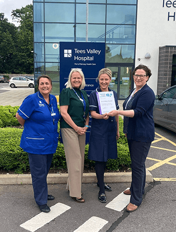 four women smiling holding a certificate