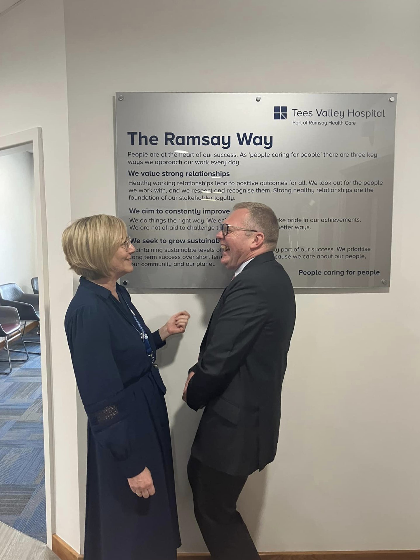 two people laughing under a hospital sign inside