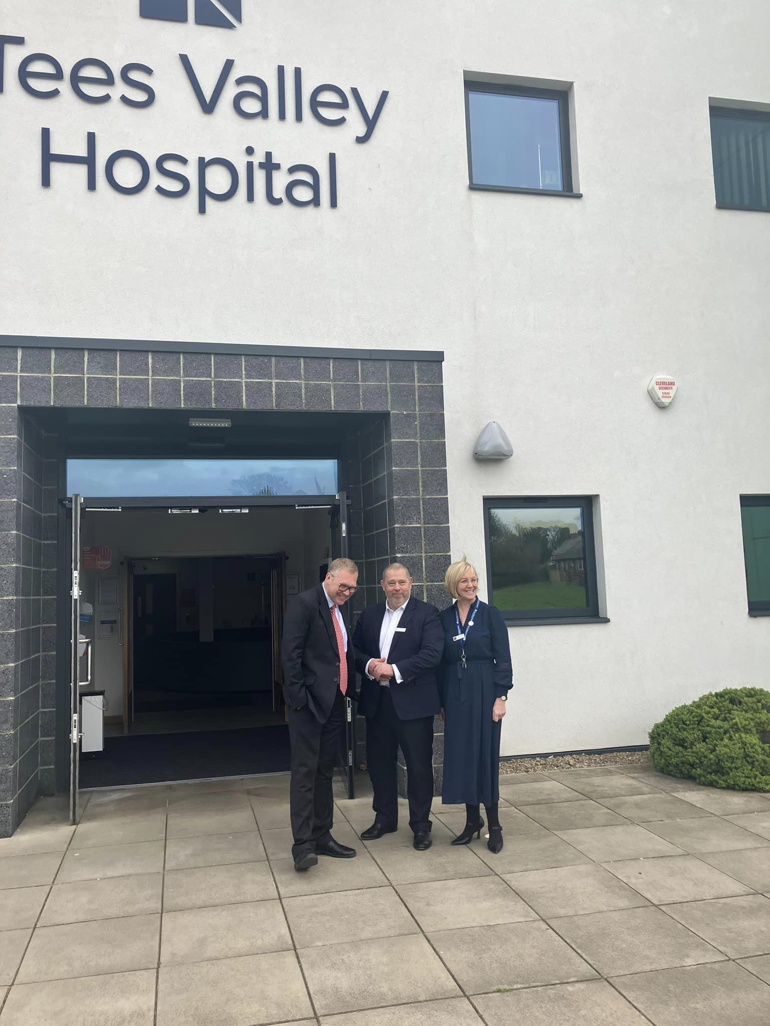 three people stood outside of a hospital smiling